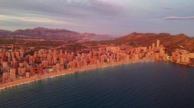 Bronz saat sıcaklığında kıyı şeridi. Sıcak turuncu renkler. Banyo yapan kumsal kuleleri ve uzak tepeli kıvrımlı körfez.