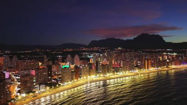 Gece vakti hava sahili parlak altın ışıklar kıyı şeridi boyunca otel cepheleri ve huzursuz okyanus altında.