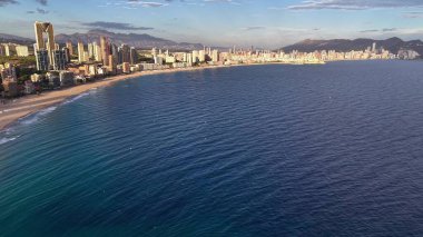 Güneşli gökdelenleri, parıldayan okyanusları ve dalgaları olan canlı kıyı boyunca öğleden sonra havası.