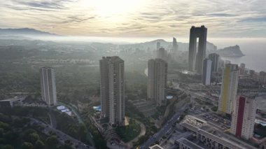 Kıyı yükseklikleri, körfezin üzerindeki altın sisli gündoğumu gökdelenleri, boş kuleler.