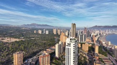 Kıyı insansız hava aracı anketi gündoğumunda parlayan gökdelenler, mavi koy, uzak dağlar, hareketli