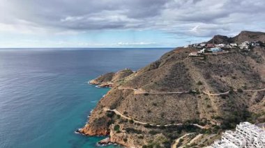 Beyazlatılmış hava manzaralı köy turkuaz körfezin üstündeki engebeli uçuruma tünemiş, kıyı şeridini birbirine bağlayan yol.