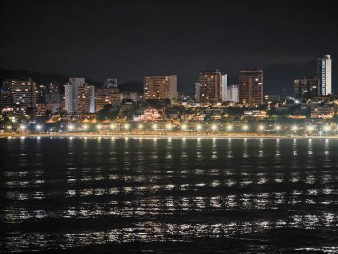 Gece rıhtımında parıldayan ışıklar ve suda yansıyan parıltılar, sokak lambalarıyla parlayan şehir kemeri.