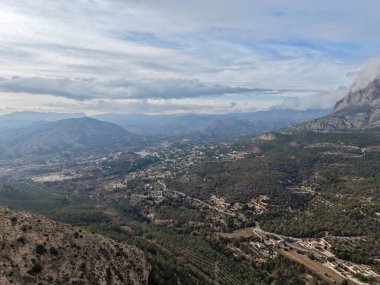 Dağılmış köyleri, zeytinlikleri, dolambaçlı yolları ve uzak tepeleri gösteren hava vadisi manzarası.