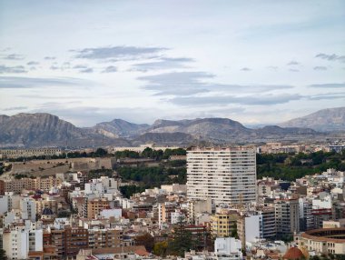 Yüksek apartman blokları şehir vadisine hükmediyor, balkonları ve beton cepheleri yığıyor, uzak dağlar