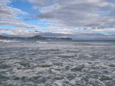 Huzursuz denizin üzerindeki kasvetli gökyüzü engin katmanlı bulutlar kaynayan sular ve köpüklü suların üzerine ışık saçıyor.