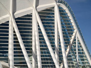 Kavisli beyaz kaburga çerçeveli cam cephe, yükselen kemerli açıklıklar ritmik gölge desenleri, yansıtıcı