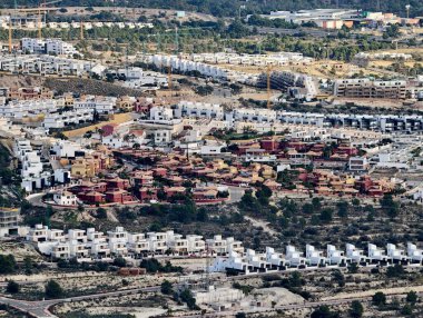 Beyaz villaları ve kurak yamaçlardaki kırmızı fayanslı çatıları olan banliyö gelişiminin havadan görünüşü,