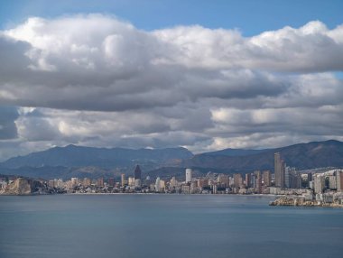 şehir kıyıları kayan bulut ışığı altında, kıyı şeridi boyunca uzanan dağlar, değişken gökyüzü