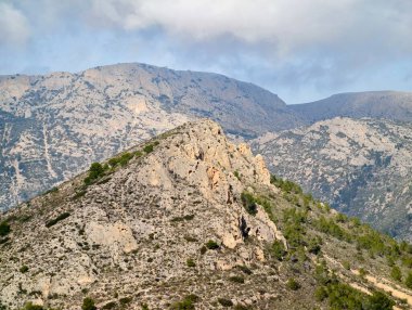 sunlit rocky ridge overlooking distant peaks and valleys, hiker viewpoint concept with golden light, scattered