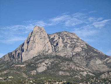dramatik kayalık tepe, dokulu yüzle canlı mavi gökyüzü altında kayalıklar ve çatlaklar, keskin çıkıntılar gösteriyor.