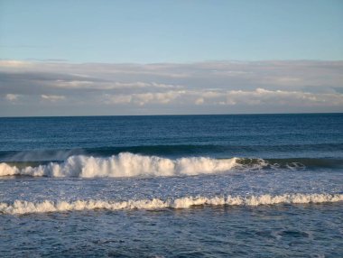 Sakin okyanus boyunca katmanlı dalga şeritleri oluşturan yumuşak sörfler, gün ortası ışığı ve hatta ufuk çizgisini bile kapatan sessiz dalgalar.