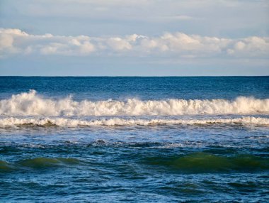 Yeşil su ve köpüklü beyaz köpükle dalgalanan dalgalar, güçlü sprey ve çarpan hareketler, dramatik kıyı.