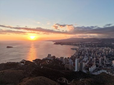 Sahil kuleleri ve yumuşak pastel gökyüzü ile körfez üzerinde sakin bir akşam manzarası ılık tonlarını yansıtan sakin sular.,
