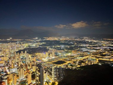 Sahil boyunca romantik gece ışıkları parlayan ufuk çizgisi arkaplanı, suyun yumuşak yansımaları, rahat