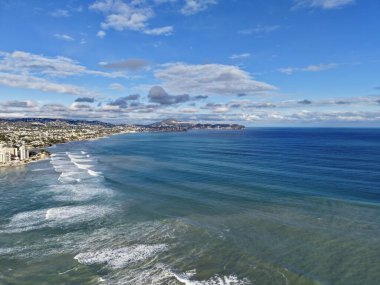 Ritmik sörf hatları ve berrak suları olan hava kıyıları, kumlu sahile doğru ilerleyen uzun dalga bantları, sakin.