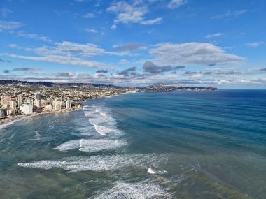 açık deniz ufkunda hafif kabarmalar ve bulutlar, ince dalga dokusuyla engin mavi alan, sakin deniz.