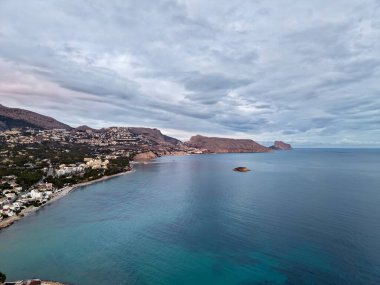 Sessiz tonlarla, yumuşak ışıklarla, kayalıklarla ve camsı sularla kaplanmış körfez, sessiz bir köy.