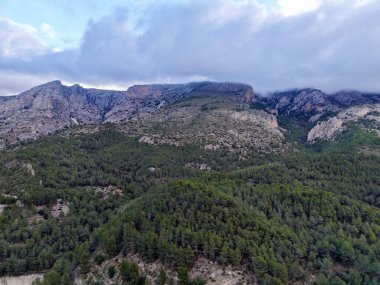 Alçak bulutlar, engebeli tepeler, atmosferik ışık saçan kasvetli dağ manzarası