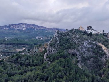 Turkuaz havza ormanına tepeden bakan puslu sırt, yumuşak sis ve bulut tabakası, sessiz tonlar, uzak tepeler.