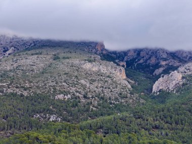 Kireçtaşı dağları ve yoğun çam ormanları üzerindeki fırtınalı bulut kümesi dramatik alçak ışık ve kara kara düşünen atmosfer,