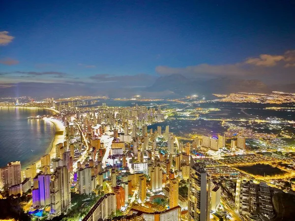 Limanda ve kıyı yollarında alacakaranlıkta araç trafiği, aydınlatılmış rıhtımlar ve nakliye düğümleri parlıyor.,