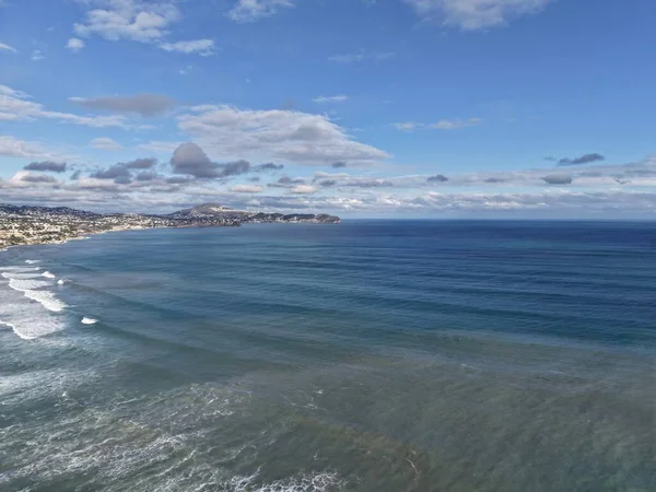 Kıyı sahili dalgaları geniş kıyı şeridini, burunları, dağınık şehirleri gösteriyor.