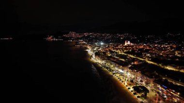 Gece havası kıyı şeridi şehir ışıkları plaj boyunca canlı, hareketli gezinti güvertesi ipuçları, parlak restoran kümeleri