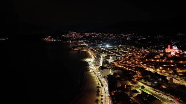 Kehribar ışıkları, işlek otel şeritleri, aydınlatma işaretleriyle dolu gece hava sahası ve sahil kenarı.,