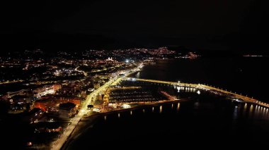 Hava gece köprüsü ışıkları liman kıvrımlı ufuk çizgisi kıvrımlı otoyolda parlıyor, trafik ipliklerini hareket ettiriyor, insansız hava aracı...