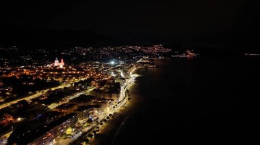 Hava gece gezinti ışıkları kıyı şeridi festivali aydınlatılmış deniz önü caddesi kıvrımları kafelerin önünden geçiyor
