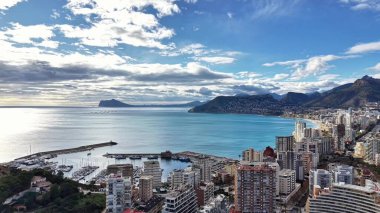 Kıyı metropolü, kümelenmiş kuleler ve marina tarafından çerçevelenmiş turkuaz körfezi, parıldayan güneş suyu