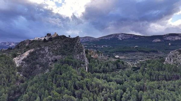 Fırtınalı tepe tepesi, çam ormanı üzerinde havadan gözetleme, kayalık kayalıkların tepesinde antik kalıntılar, dramatik bir keşif.