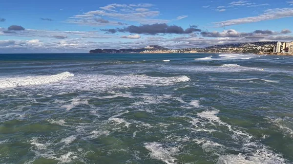Çalkantılı yeşil sörf sahil kayalıklarını silip süpürüyor, güçlü dalgalar, sprey ve dalgalar, dramatik rüzgarlı su