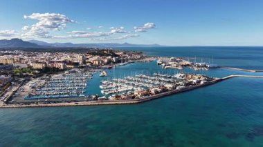 Marinanın üzerinde düzenli yatları olan bir kıyı manzarası sakin turkuaz deniz, uzak dağ sırtı, nazik