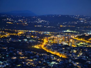 Dolambaçlı otobanın gece görüşü altın tonlar, konut kümeleri ve çerçeve uzak tepeler