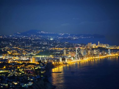 Gece vakti şehir ışıkları kıyı şeridi boyunca canlı sahil bulvarı sergiliyor.