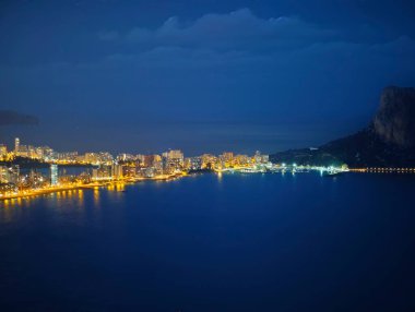 Şehir kurdeleli hava gece manzarası kıyı şeridini takip ediyor, yoğun binalar parlıyor.