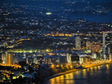 Geceleri aydınlık kıyı boyunca uzanan kule kümesi modern binaların dikey siluetleri yoğun kıyı şeridi boyunca uzanır.