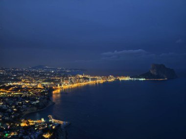 Gece aydınlık kıyı şeridinde yüksek kümeler, yoğun kıyı silüeti oluşturan yüksek binalar, sıcak
