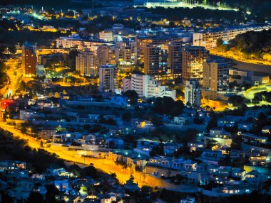 Geceleri kıyı şeridi boyunca aydınlık caddeler, göbek binaları arasında uzanan sıcak sokak lambaları.,