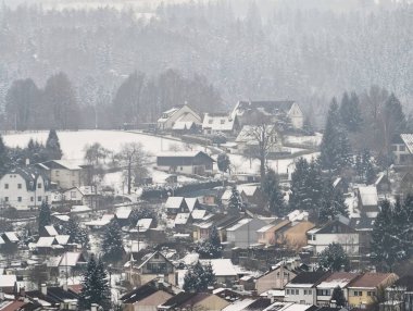 Sisli yamaçlarda karla kaplı bir köy kümelenmiş çatılar, dar sokaklar, dağınık her yer yeşillik, uzak