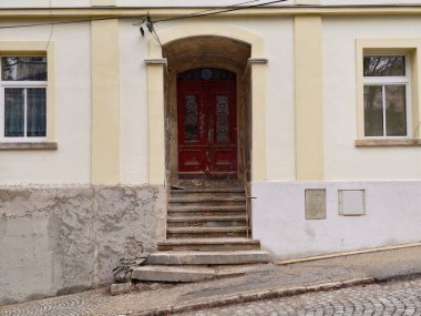 Kırmızı kapı taşı, sarı cephe, süslü kemer yolu ve yıpranmış sıva, kaldırım taşı yaklaşımı, klasik pirinç.