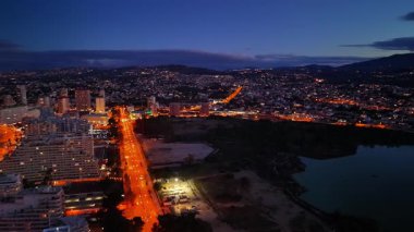 Alacakaranlık Bulvarı ışıkları kıyı şeridi parıltısı ana cadde şehrin içinden uzak tepelere doğru gidiyor, turuncu.