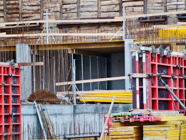 İnşaat altındaki beton çerçeve demire maruz kaldı, biçimlendirme panelleri, yoğun yapı iskelesi, sarı güvenlik rayları,