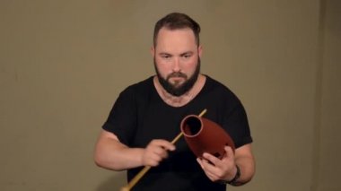 Siyah T-Shirt sakallı adam, Parlak Duvarların Arka Planda Perküsyon Enstrüman Guiro Playing