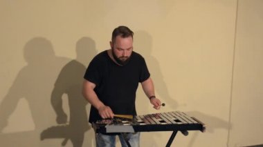 Siyah T-Shirt, vurmalı enstrüman çan parlak duvarlar arka plan üzerinde oynarken bir sakallı