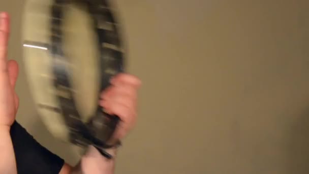 Ein Mann spielt auf dem Schlaginstrument Tamburin. auf dem hellen Wandhintergrund. — Stockvideo