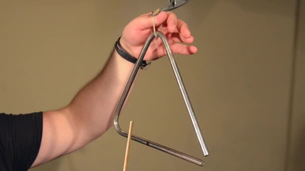 Un hombre tocando en el Triángulo del Instrumento de Percusión. sobre el fondo de las paredes brillantes . — Vídeos de Stock