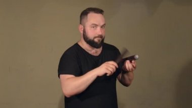 Siyah T-Shirt, vurmalı enstrüman anahtar kelimeler üzerinde oynarken bir sakallı bir adam. Parlak duvarlar arka plan üzerinde.